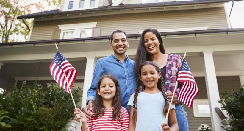 Portrait Of Family Outside House Holding American Flags