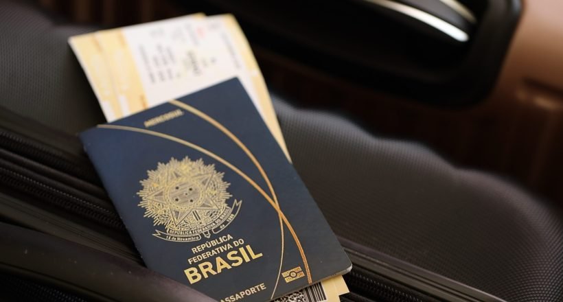 Federative Republic of Brazil passport with tickets lies on touristic suitcase close up in airport waiting hall. Travel worldwide and international tourism concept S