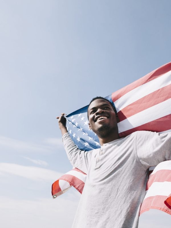 smiling-black-man-holding-waving-american-flag-back-scaled.jpg